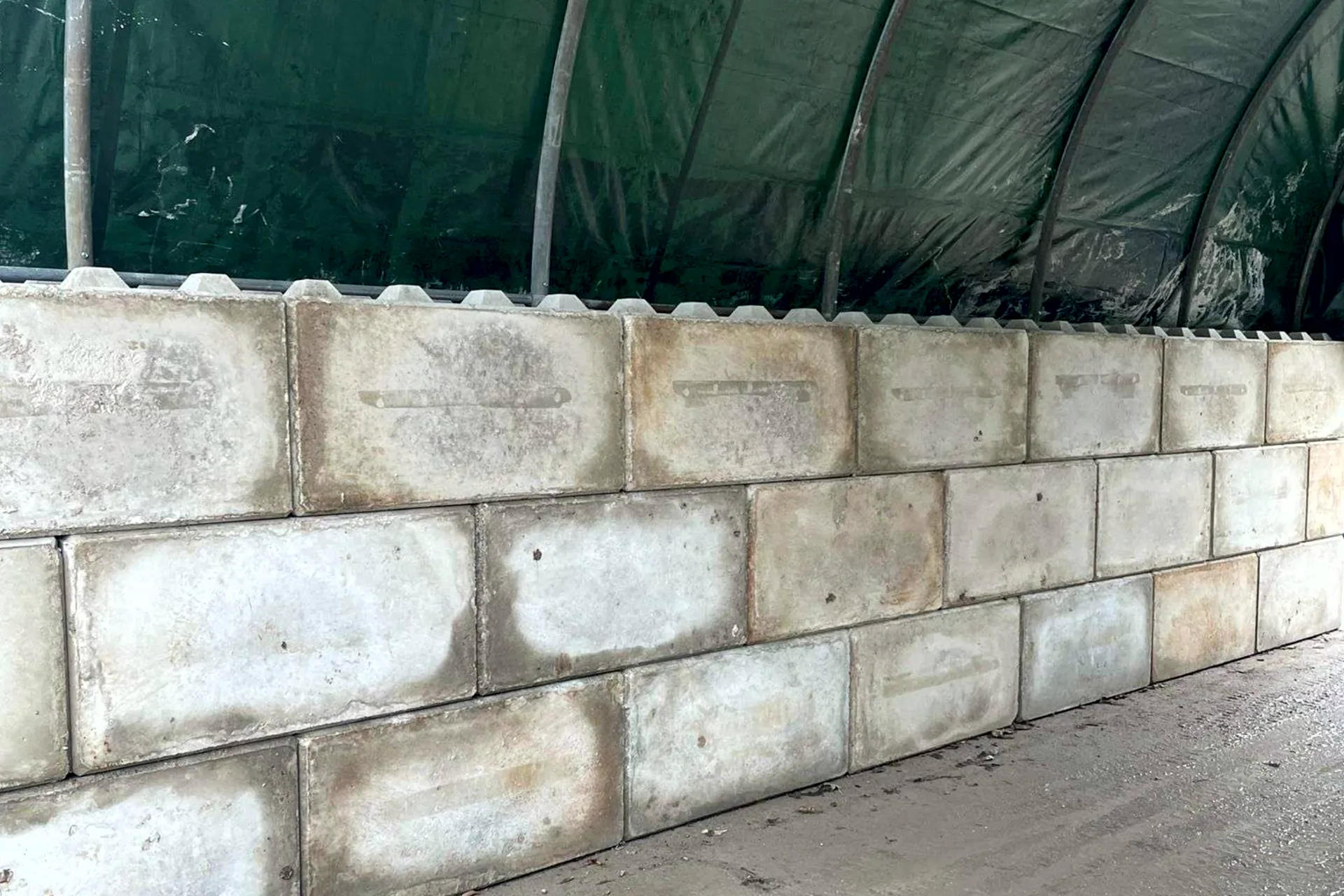 Gestapelte Betonblöcke als Fundament einer Rundbogenhalle